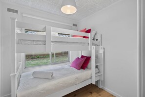 Dormitorio con literas, ventana, paredes blancas y lámpara en el techo.