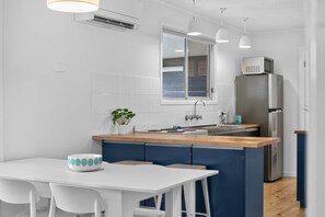 A modern kitchen with a central island, white cabinetry, and a stainless steel refrigerator. - Beach and Birdies at Goolwa (Goolwa South)