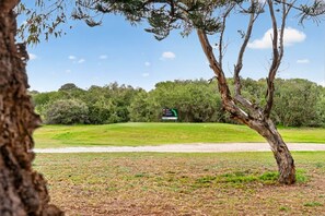 Campo de golf con un cartel que indica un hoyo, rodeado de árboles y cielo despejado.