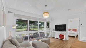 Una sala de estar moderna con un televisor grande, asientos cómodos y vistas al exterior.