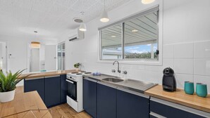 Una cocina moderna con una isla central, horno empotrado y un amplio ventanal con vistas.