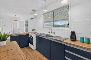 Eine moderne Küche mit einer zentralen Kochinsel, einem Einbauofen und einem großen Fenster mit Blick.