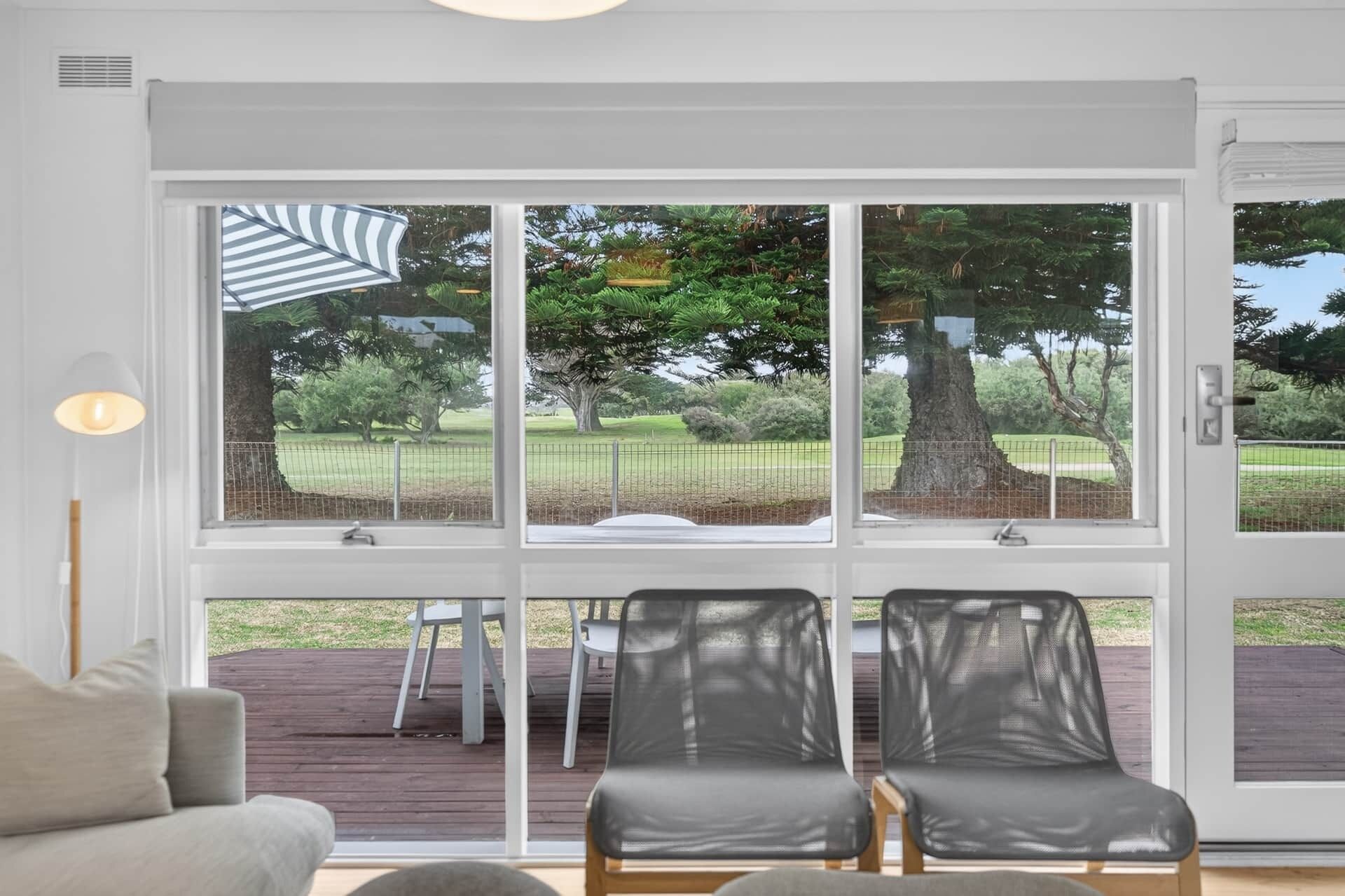 A room with a large sliding glass door leading to an outdoor deck with two chairs and a table.