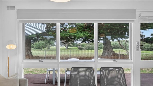 Una habitación con un amplio ventanal corredero que da a una terraza exterior con dos sillas y una mesa.