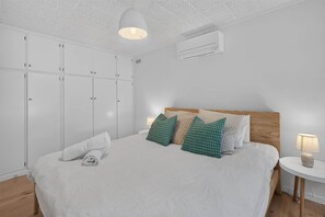 Un dormitorio con una cama, un armario, una mesita de noche y una lámpara.