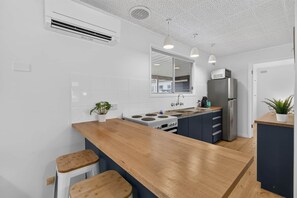A modern kitchen with a wooden island, stainless steel appliances, and a large window. - Beach and Birdies at Goolwa (Goolwa South)