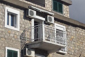 A stone building with a balcony, air conditioning units, and shutters. - Villa Teodora Mare - One-Bedroom Apartment with Balcony and Sea View (App 3) (Petrovac na Moru)