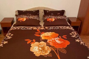 Ein Bett mit blumigem Überwurf und passenden Kissen, zwei Nachttische und ein Holzkopfstück.