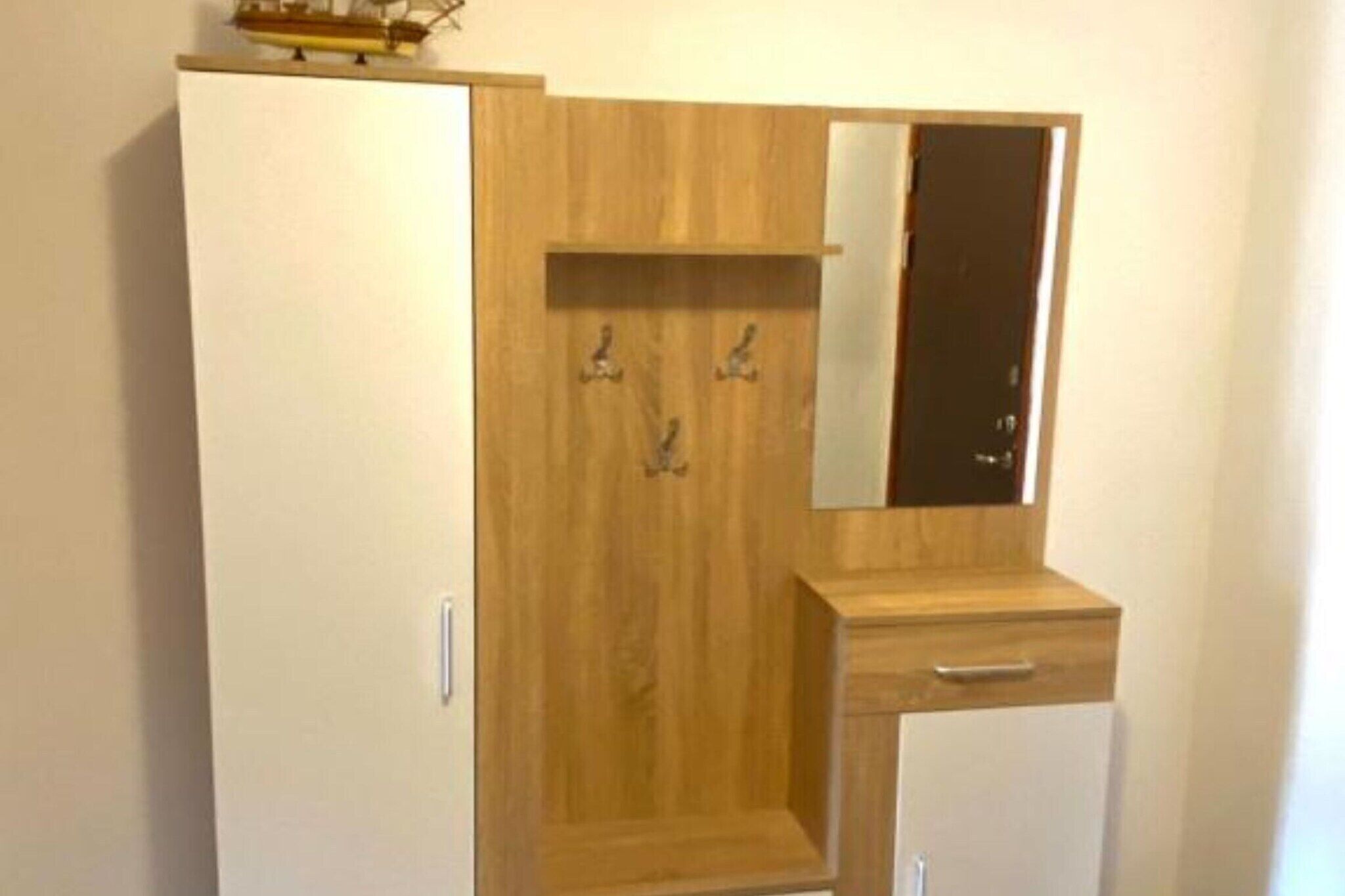 Un armario con un espejo y un pequeño mueble.