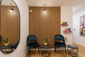 Una habitación moderna con dos sillas oscuras, una mesita, un espejo y una pared de listones de madera.