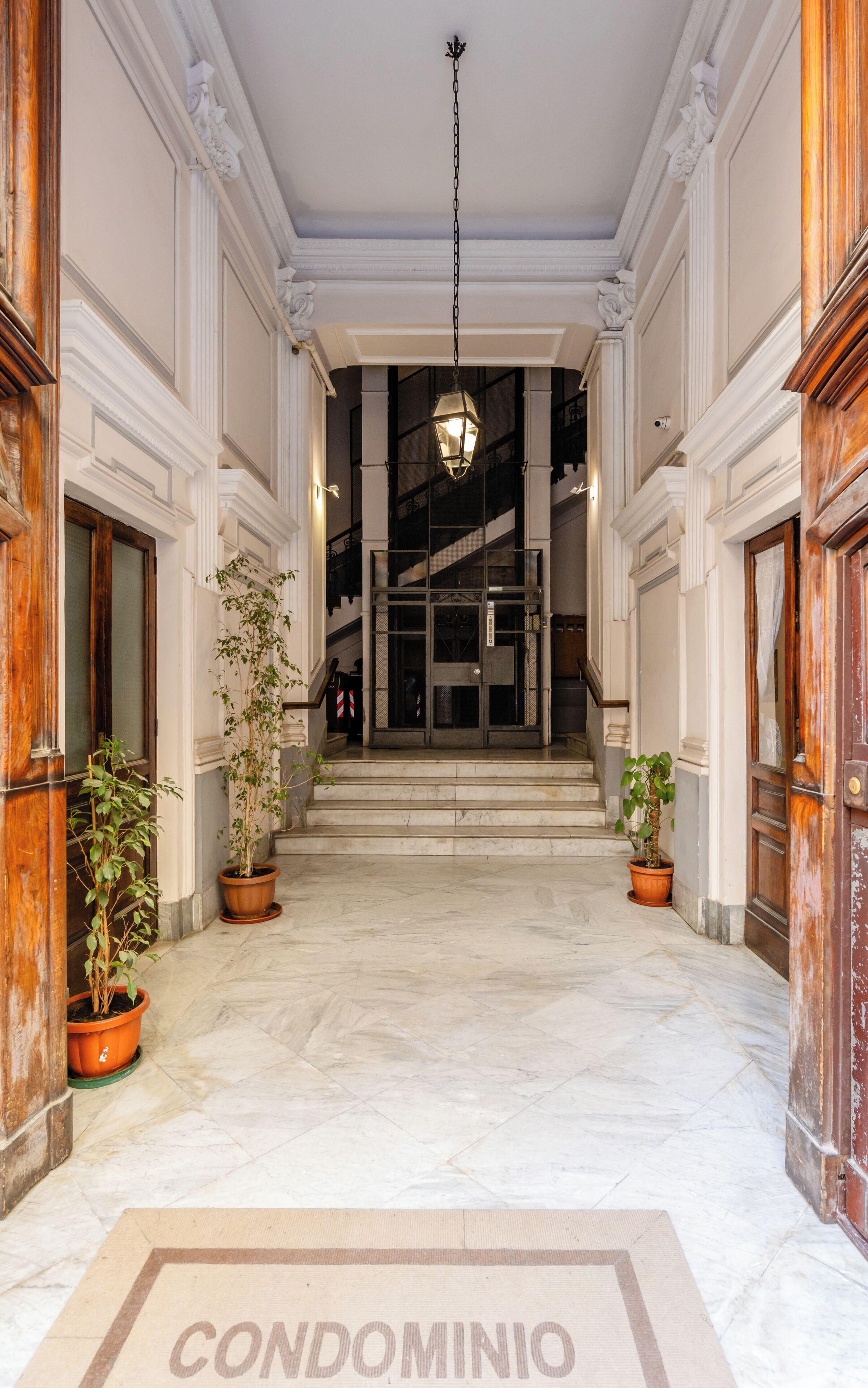 A grand entrance with marble flooring, a central staircase, and a chandelier.