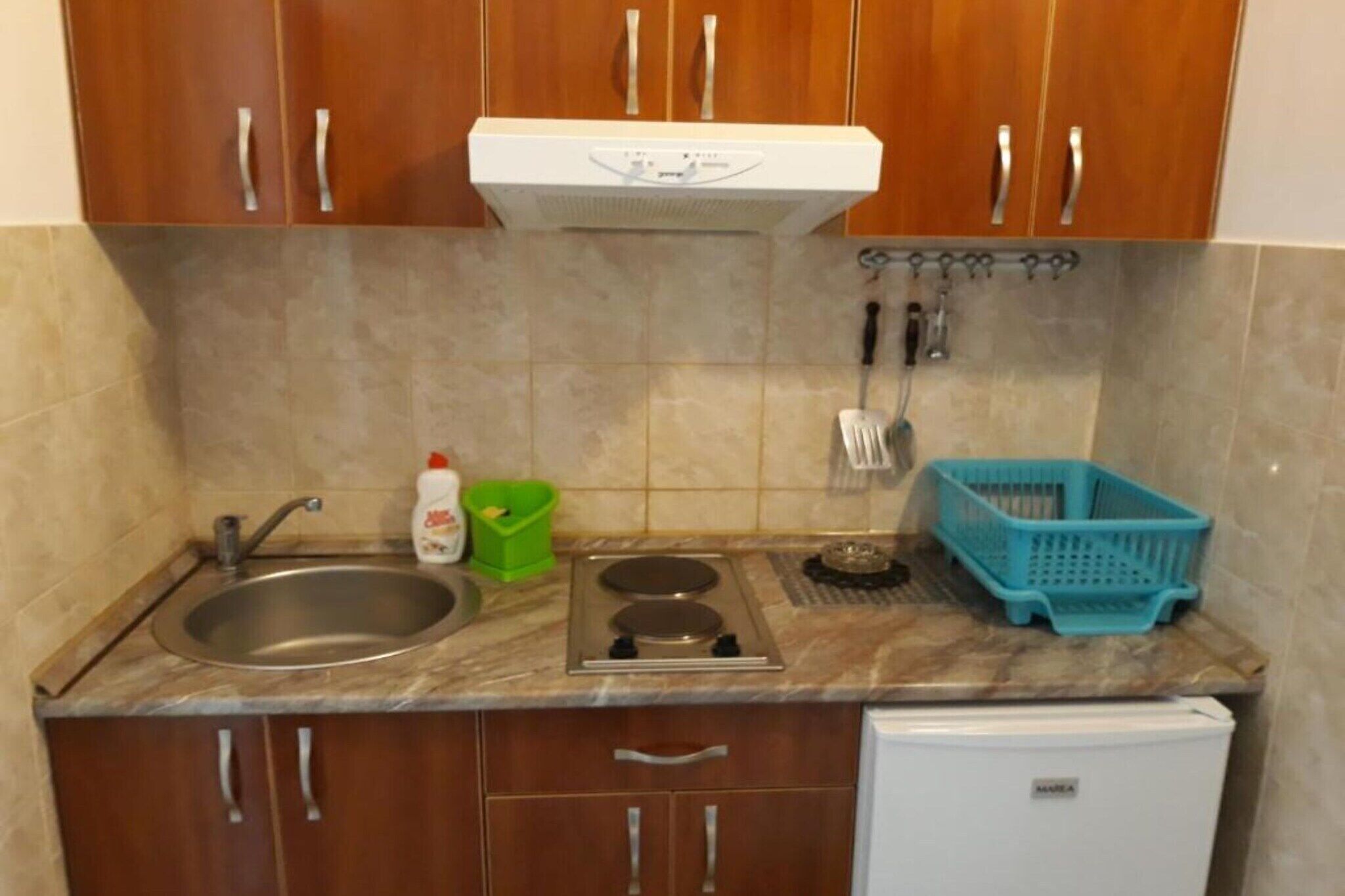 Eine kleine Küche mit Spüle, Herd und kleinem Kühlschrank.