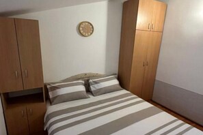 Ein Schlafzimmer mit einem Bett, zwei Kissen, einem Holzschrank und einer Wanduhr.