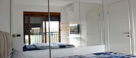 Un dormitorio con cama, televisor y puerta corredera.