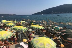 Ein überfüllter Strand mit vielen Sonnenschirmen und Liegestühlen.