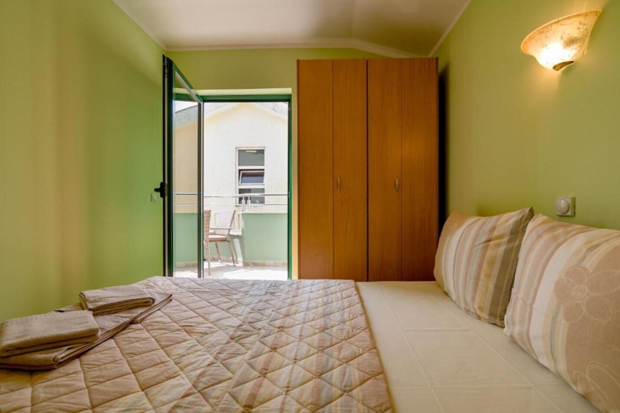 A bedroom with a bed, a wardrobe, and a small balcony.