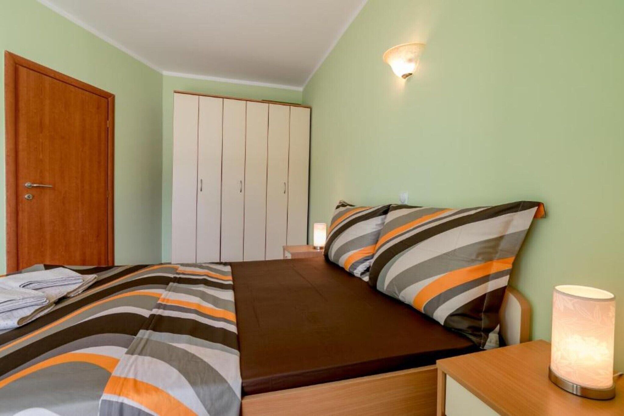 Un dormitorio con cama, armario y mesita de noche con lámpara.