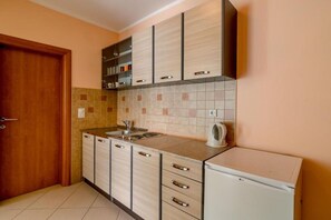 Eine kleine Küche mit Spüle, Schränken und einem Kühlschrank.