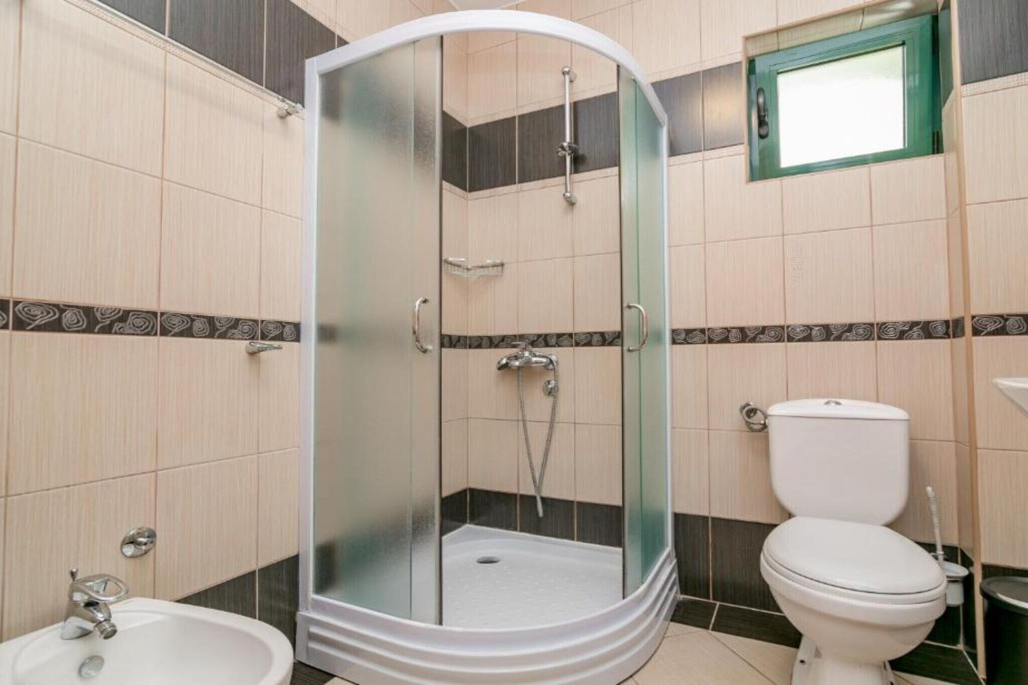 Un baño con ducha envuelta en vidrio, inodoro y bidé.