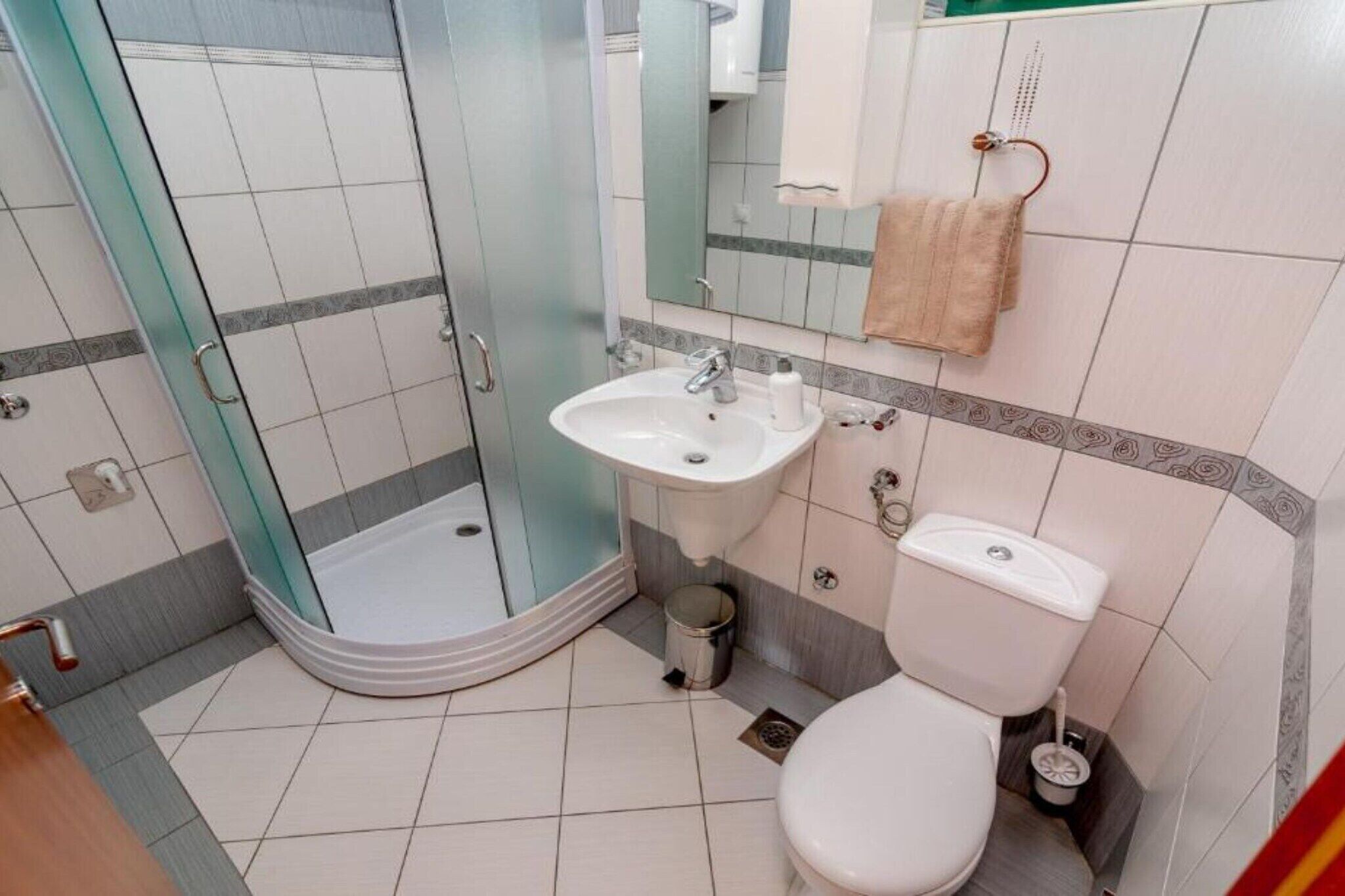 Ein Badezimmer mit Dusche, Waschbecken, Toilette und Mülleimer.