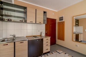Una cocina moderna con lavavajillas incorporado, cafetera y una puerta roja.