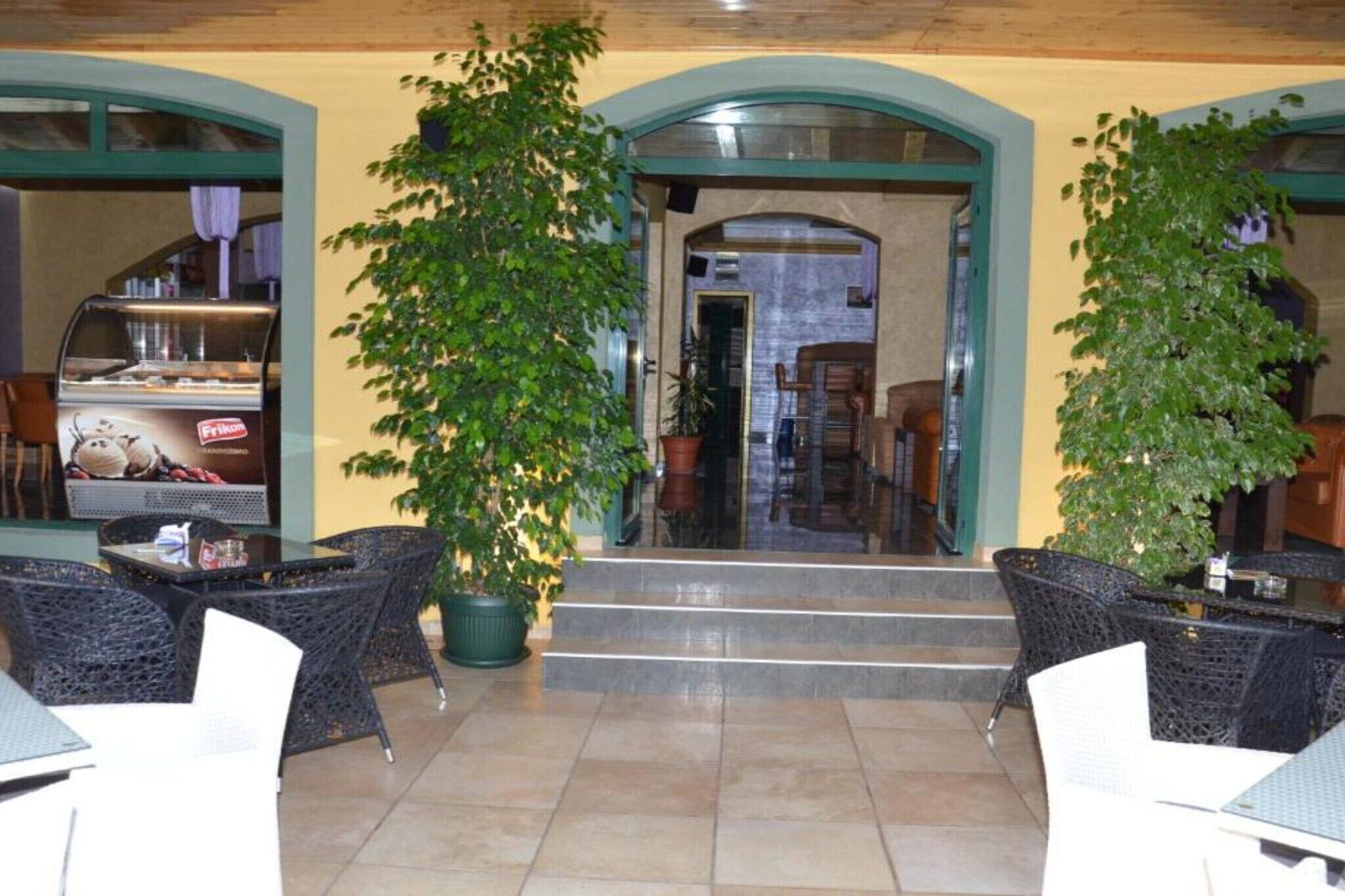 An indoor seating area with tables and chairs, a staircase leading to an upper level, and potted plants.