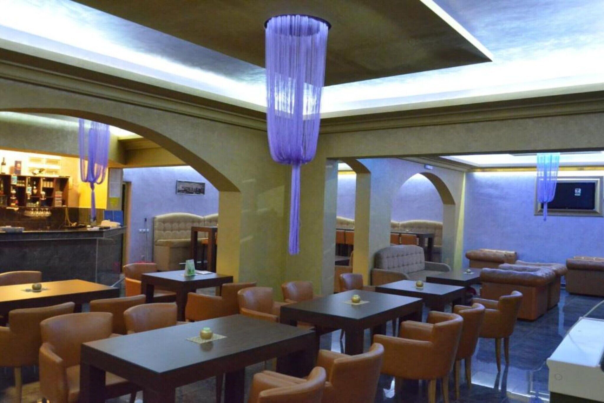Un ristorante con tavoli e sedie, una zona bar e un'area salotto con divani.