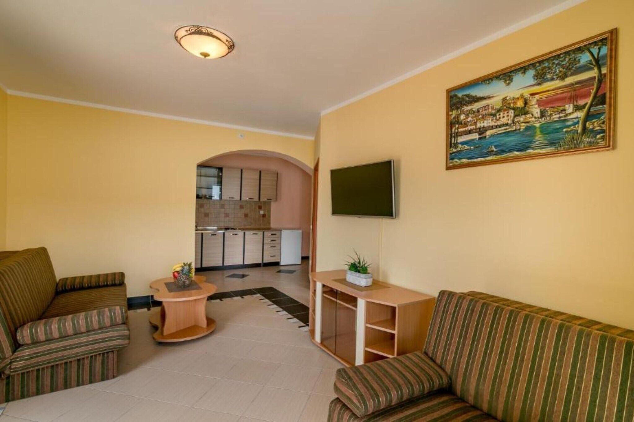 A living room with striped sofas, a coffee table, a TV, and a painting on the wall.