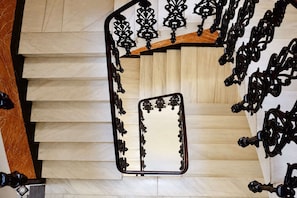 Una escalera de madera con barandillas de metal negro ornamentado y un pasamanos.