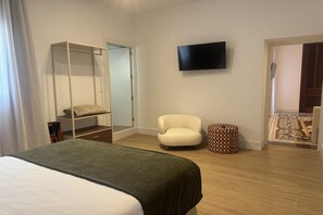 A hotel room with a bed, a chair, a television, a wardrobe, and a patterned rug. - standard suite, Caudete, Albacete (Caudete, Albacete)