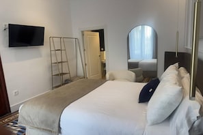 Una habitación de hotel con una cama, un televisor montado en la pared, una escalera, un espejo y una puerta que da a un baño.