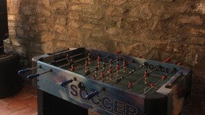 Uma mesa de futebol de mesa com a palavra 'SOCCER' nela, encostada a uma parede de pedra.
