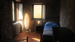 Um quarto com uma cama, abajur, radiador e janela.
