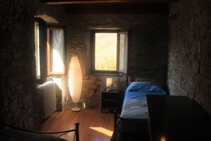 Ein Zimmer mit einem Bett, einer Lampe, einem Heizkörper und einem Fenster.