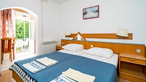 A hotel room with a bed, bedside tables, a radiator, a window with curtains, and a painting on the wall. - Apartments Klis -studio Apartment With Terrace - 2 (Zupa dubrovacka)