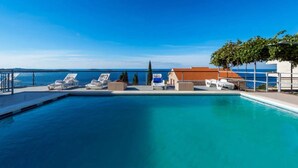 A swimming pool with lounge chairs and a view of the sea. - Apartments Klis -studio Apartment With Terrace - 2 (Zupa dubrovacka)