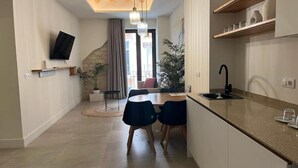 A modern kitchen with a dining area, a flat-screen TV mounted on the wall, and a staircase leading to an upper level. - Deluxe quadruple apartment (Alicante)