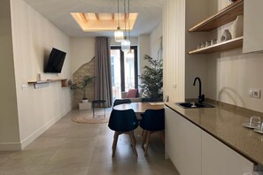 Eine moderne Küche mit Essbereich, einem flachbildfernseher an der Wand und einer Treppe, die in eine obere Etage führt.