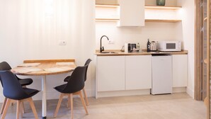 A compact kitchen with a dining area, a microwave, a kettle, and a small cabinet. - Deluxe quadruple apartment (Alicante)