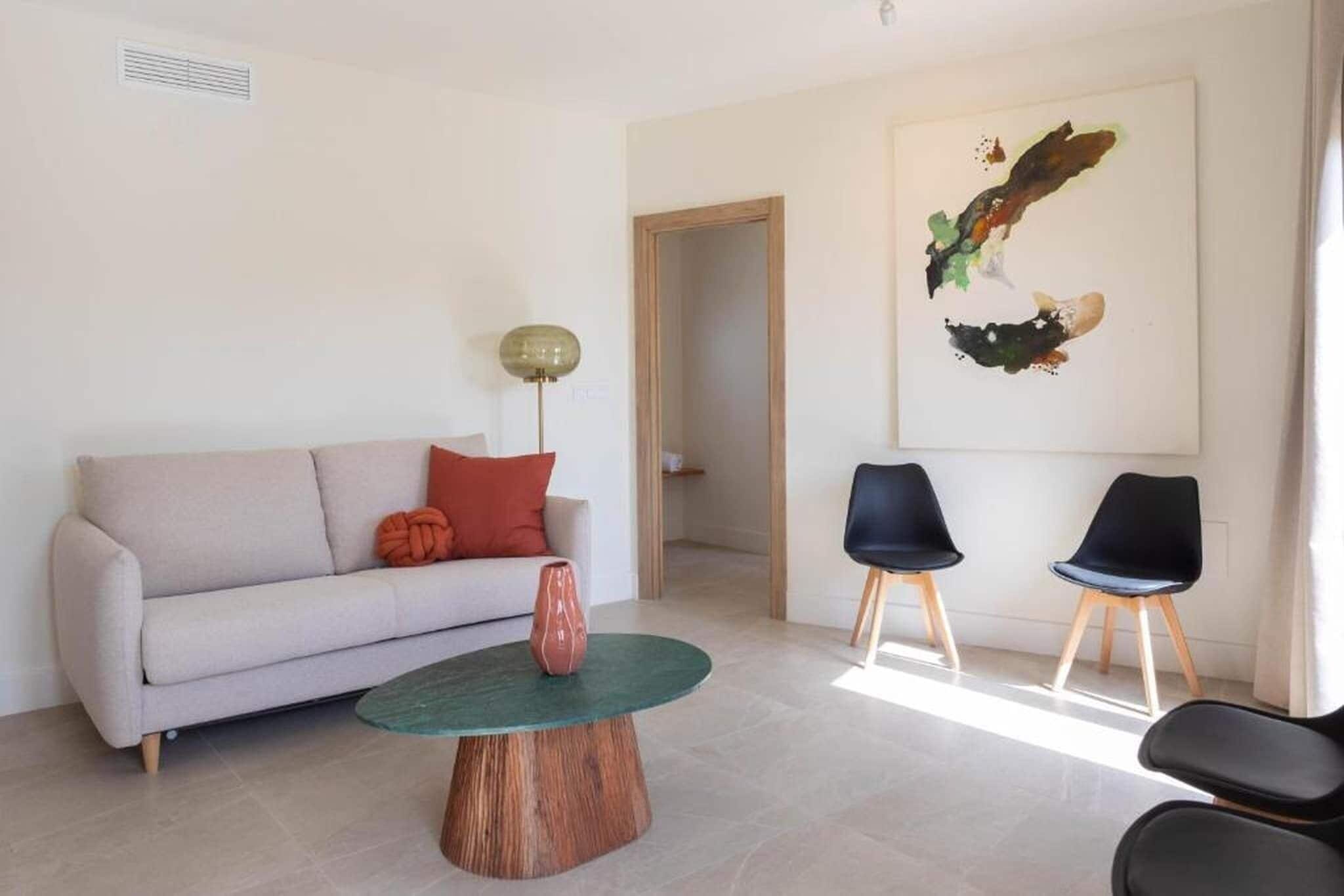 Un salon avec un canapé, deux fauteuils, une table basse et un tableau accroché au mur.