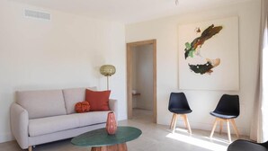 A living room with a sofa, two chairs, a coffee table, and a painting on the wall. - Deluxe quadruple apartment (Alicante)