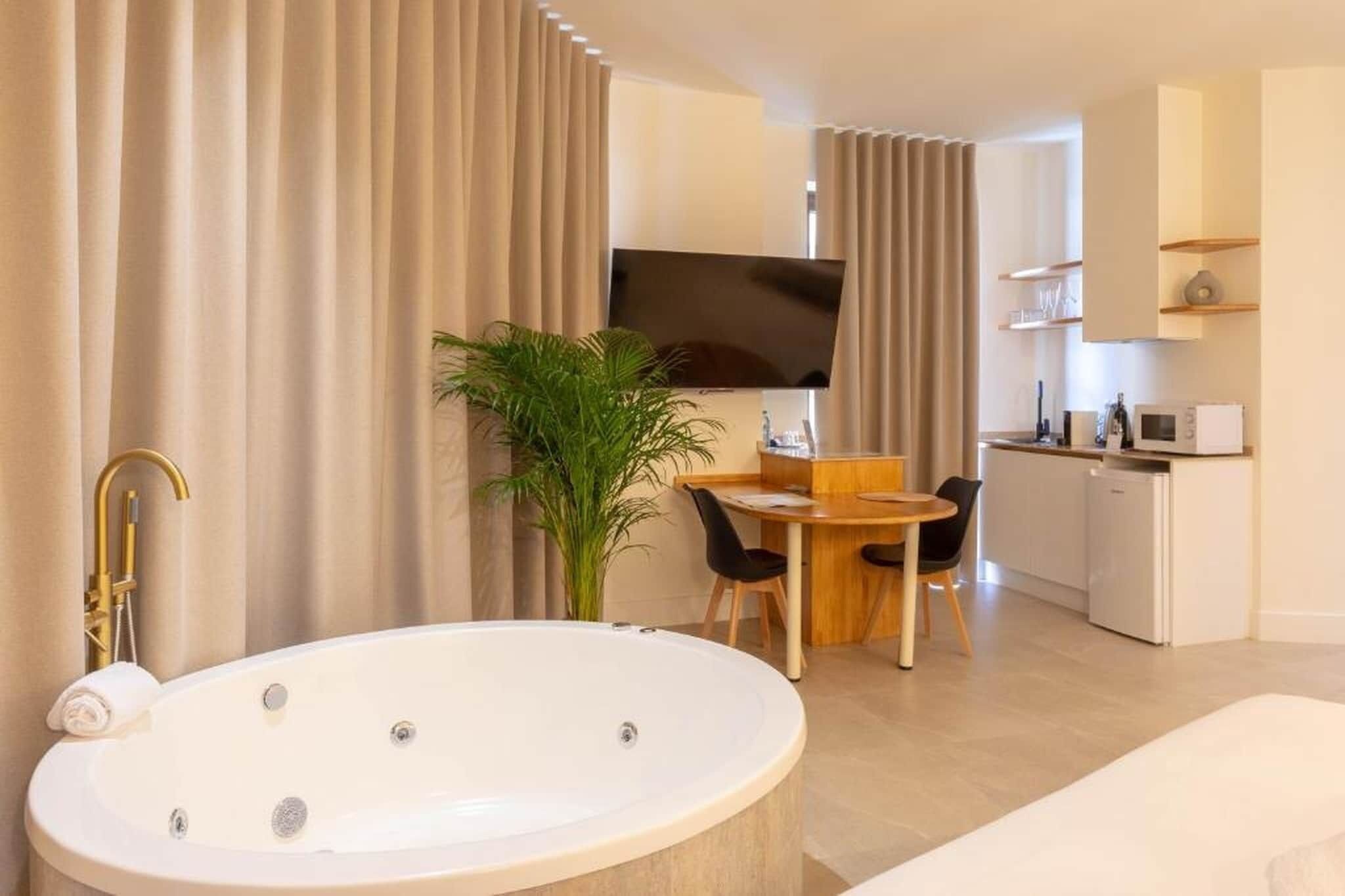 A modern bathroom with a freestanding bathtub, a shower area, and a dining area with a table and chairs.