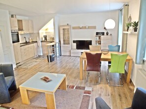 Ein modernes Wohnzimmer mit Küche, Essbereich und Sitzgelegenheiten.