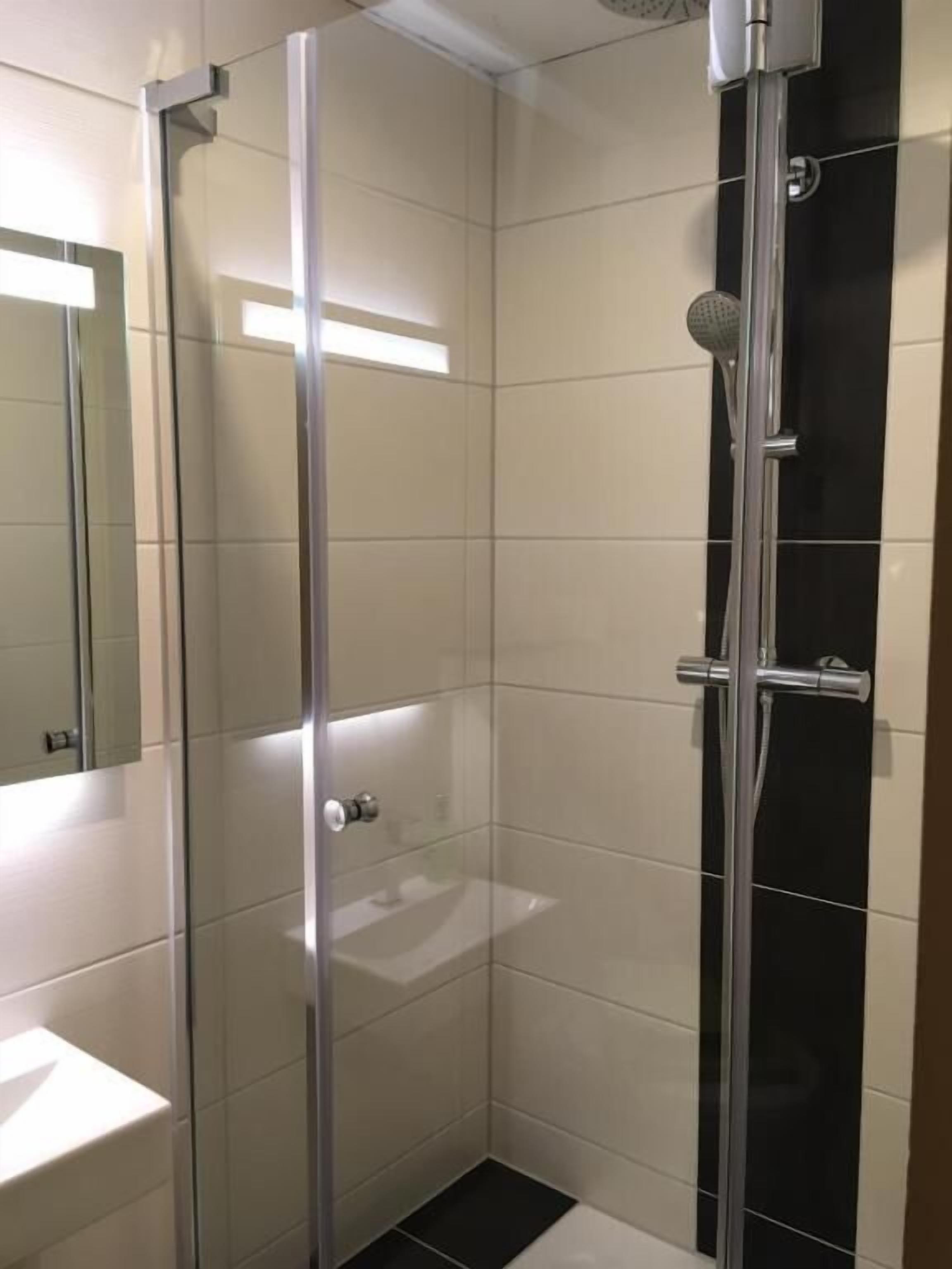 Eine Duschkabine mit Glastüren, einem Chromarmaturenset und einer Handbrause.