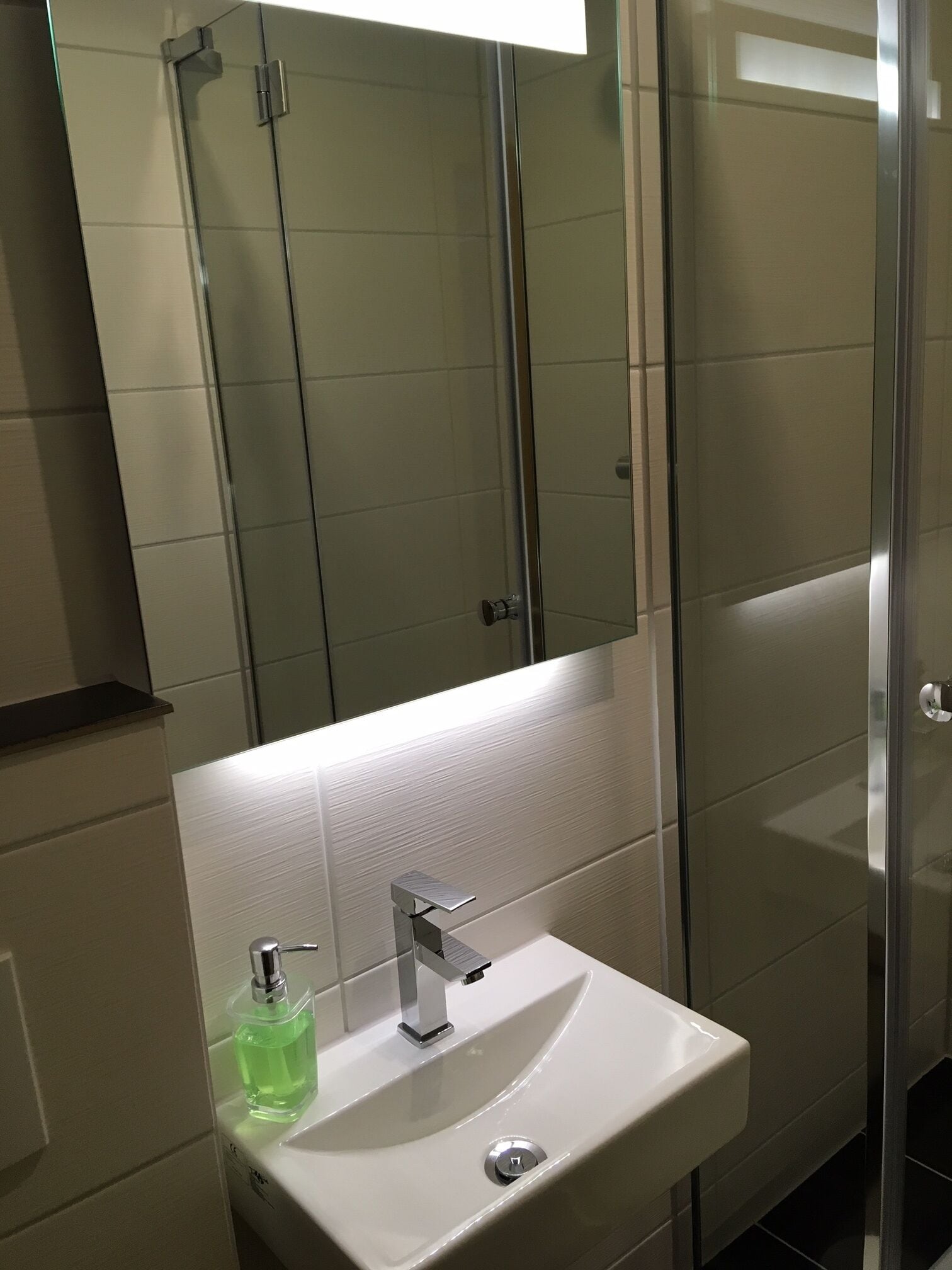 Un baño con lavamanos blanco, un espejo y cabina de ducha de vidrio.