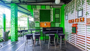 Restaurante com decoração verde e branca, banquetas pretas e um piano.