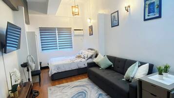 A modern bedroom with a bed, a sofa, a desk, and a marble-patterned rug.