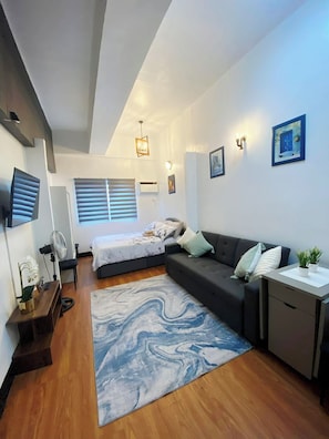 A modern bedroom with a bed, a sofa, a desk, and a marble-patterned rug. - Relax in a Cozy & Comfortable Studio across Robinsons Galleria (Cebu City)