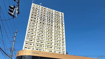 A multi-story building with a flat facade, a large parking garage below, and a clear blue sky above.