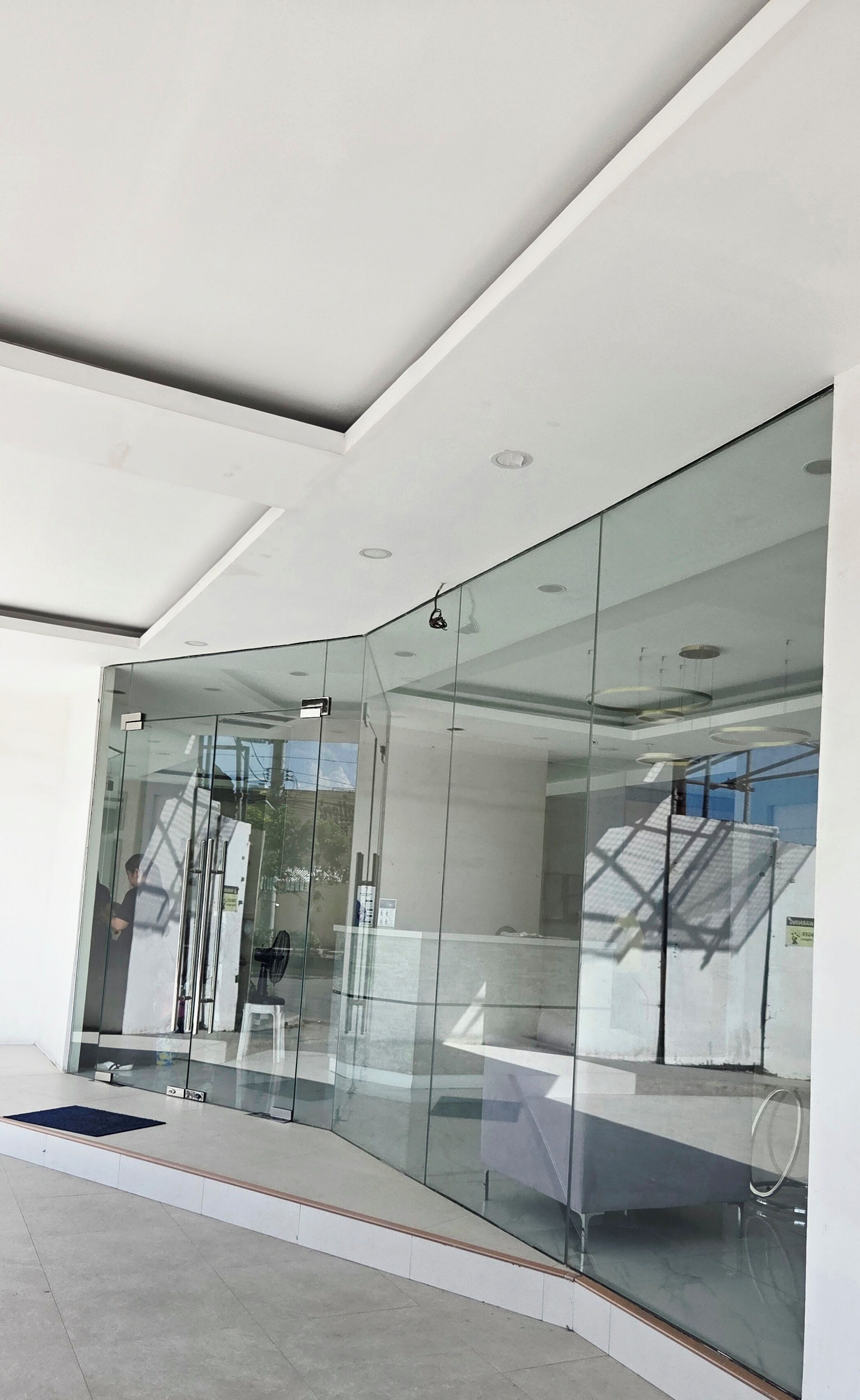 A modern building entrance with glass doors, a clear view of the interior, and a visible staircase.